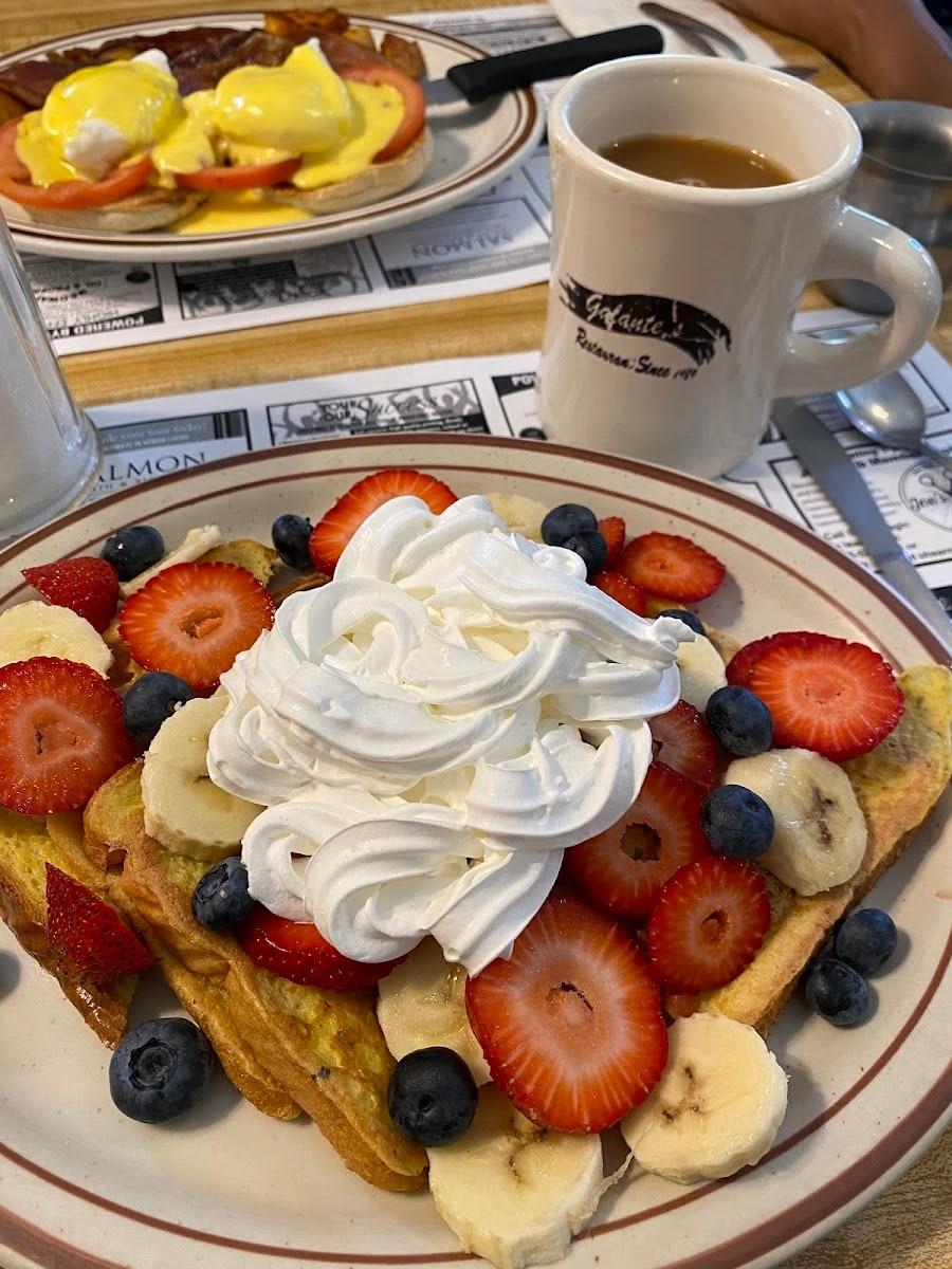 Fruitopia topped with whipped cream beside a Galante’s mug of coffee, with a Benedict on the plate behind.
