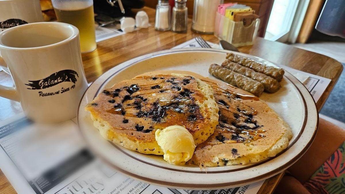 Blueberry pancakes with butter and syrup and sausage links, next to coffee in a Galante’s Restaurant mug.